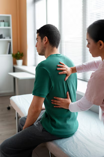 Allied healthcare professional assessing a patient with back pain, illustrating gaps in workplace injury management, such as delayed treatment and insufficient focus on musculoskeletal health.